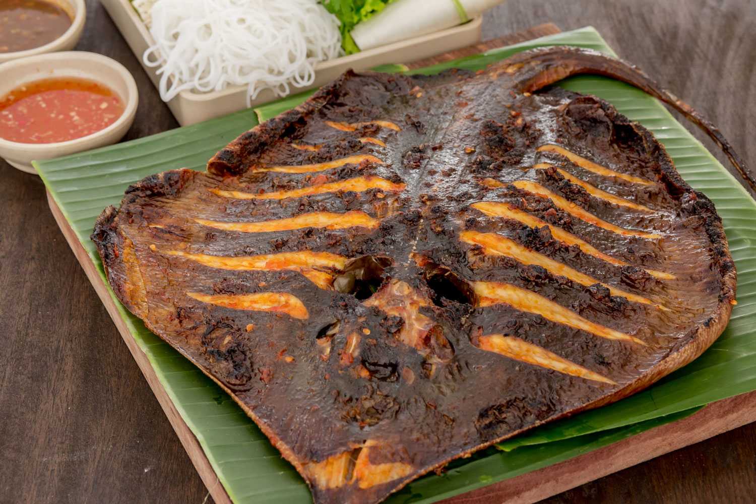 Cá đuối nướng, giòn được cuốn cùng bánh tráng và các loại rau thơm.