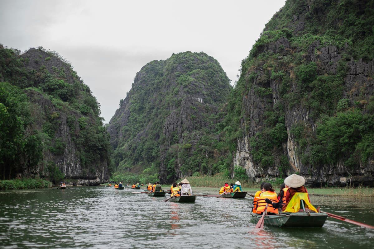 The limestone valleys of Trang An reflect like mirrors in the emerald water below.