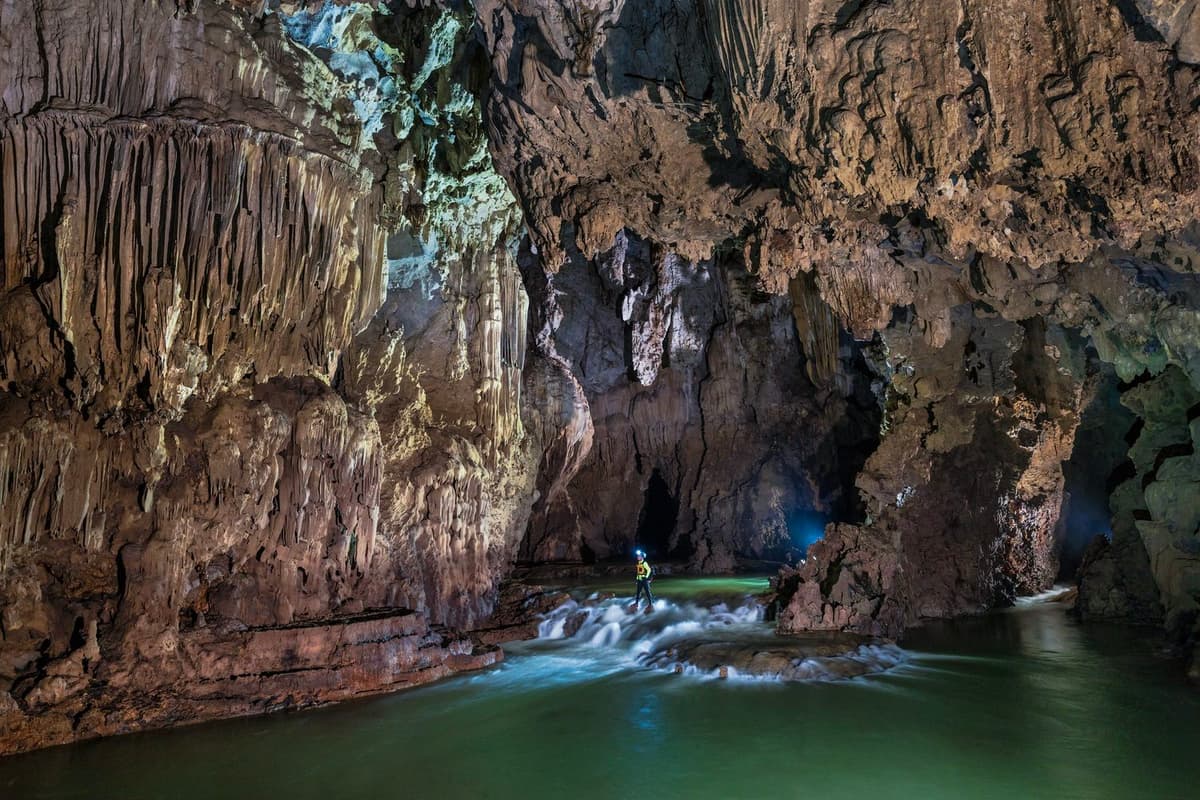 The magnificent stalactite formations and underground river in Kim Cave, part of the Tu Lan cave system.